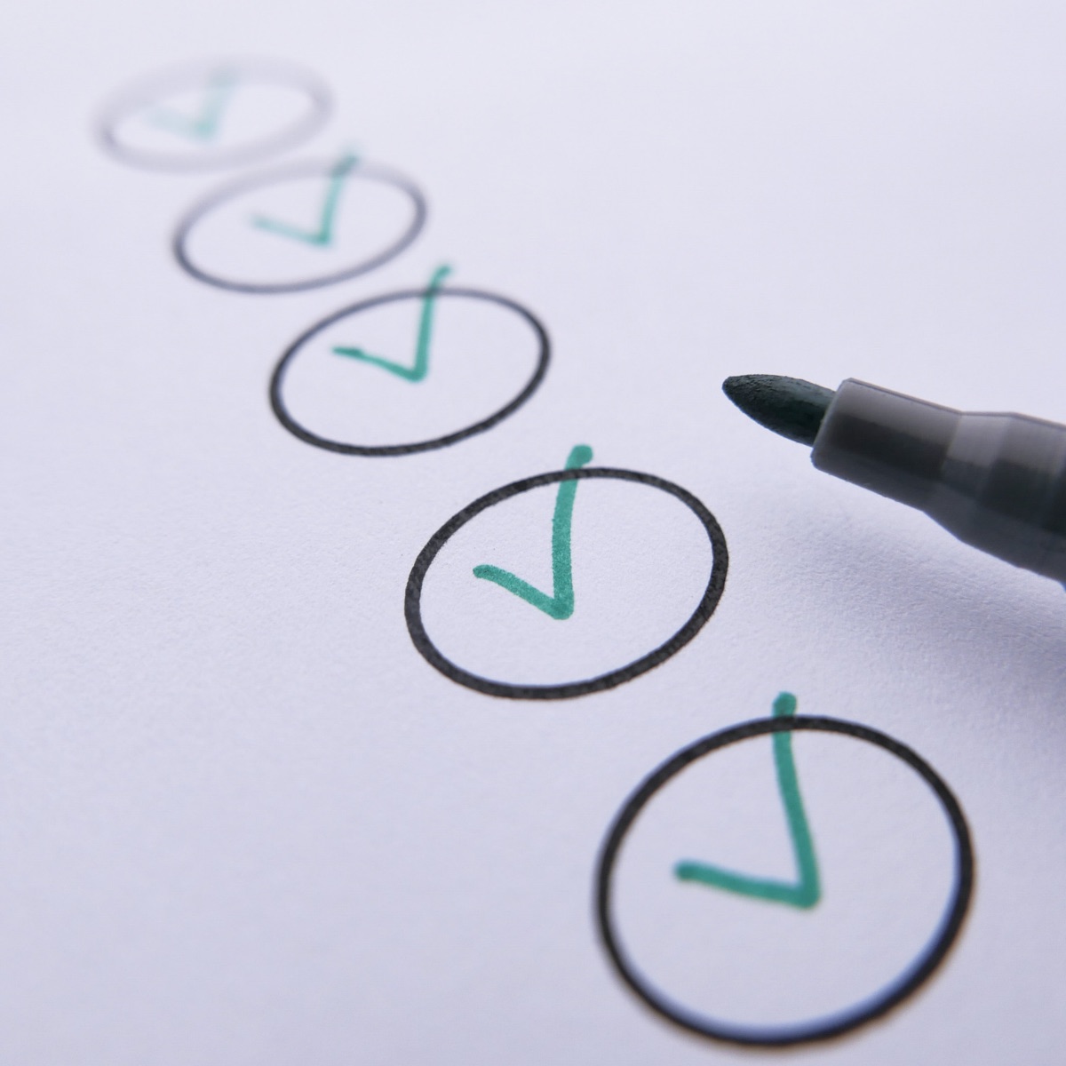 A checklist of green ticks in circles with a marker pen