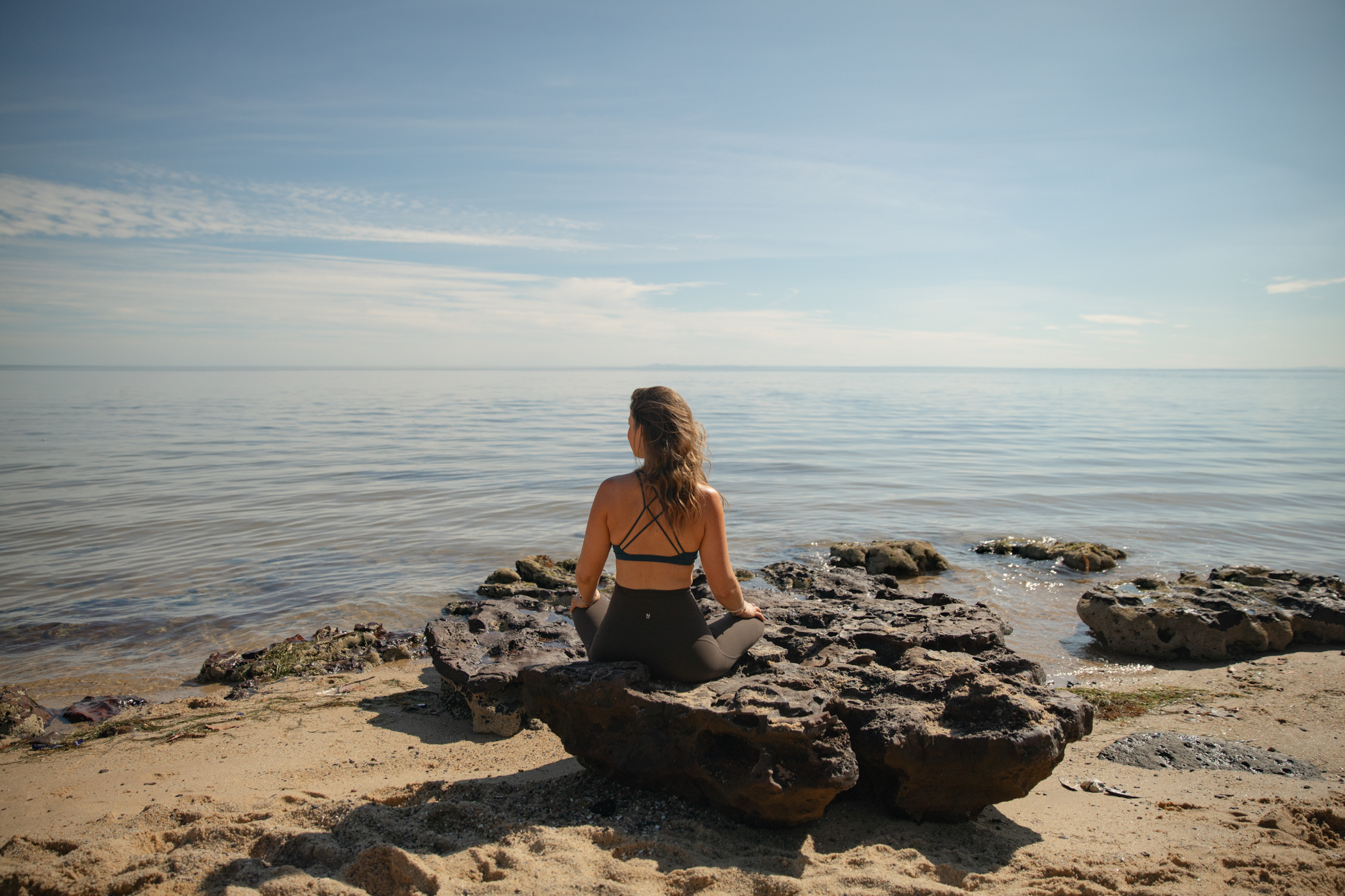 Kim Yates sitting by the ocean, looking out at the waves