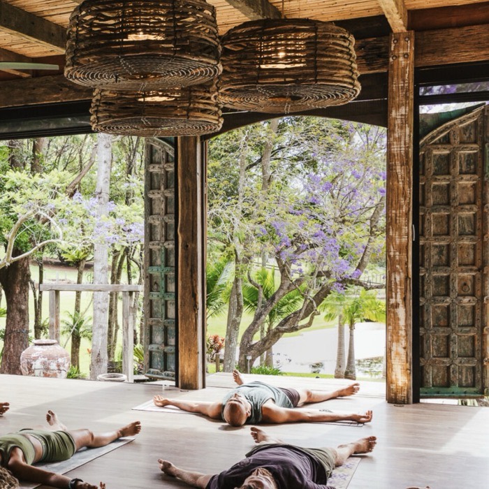 A yoga class resting in an open-air pavilion surrounded by jacaranda trees in the Byron Bay hinterland